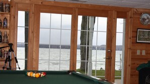 A pool table with a view of a lake through large windows. - Large  Lakefront Home on Burt Lake, ICE FISHING Hunting, fishing snow sking golf (Cheboygan)