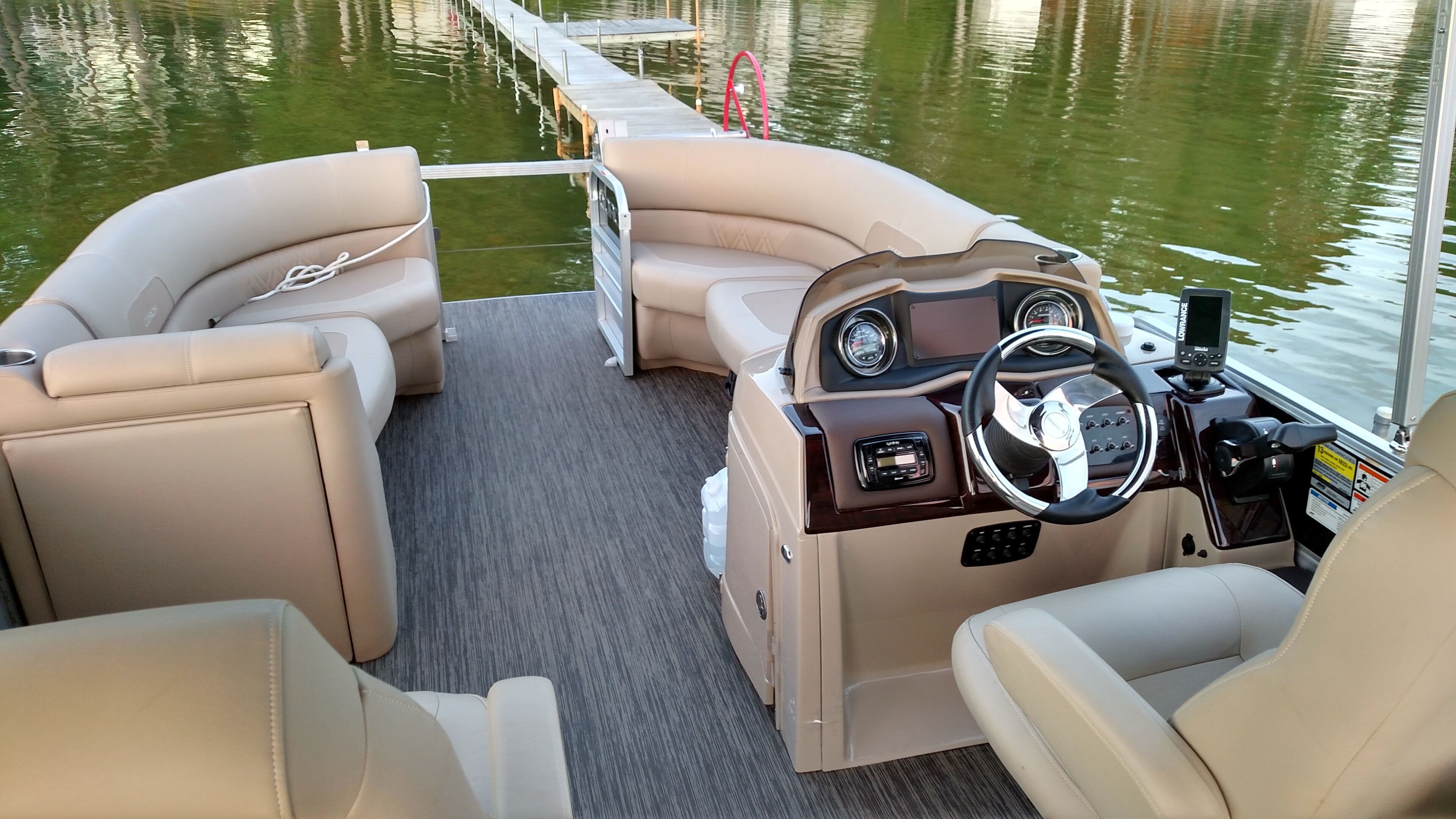 L'intérieur d'un bateau, avec deux sièges beiges rembourrés, un volant et un panneau de commande doté d'indicateurs.