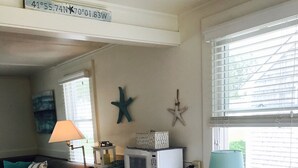 A dining area with a wooden table, white chairs, and a microwave on the counter.