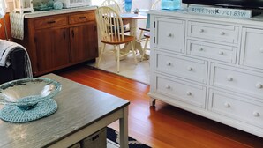 A kitchen with wooden cabinets, a white dresser, a television, and a dining area with a table and chairs.