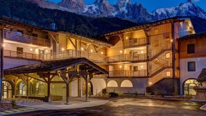 A multi-story building with a wooden facade, balconies, and a covered entrance area. - 65m2 apartment, sleeps 6/7, lake and Mont Blanc view in ***** spa residence (Chamonix-Mont-Blanc)