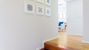 Ein Korridor mit Holzboden, weißen Wänden und gerahmten blauen und weißen Kunstwerken.