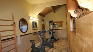 Un gimnasio con equipo de ejercicio, una pared de madera y piso de baldosas.