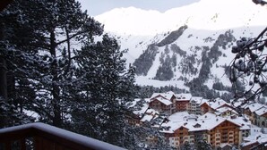 Un centro turístico en la montaña cubierto de nieve, con varias edificaciones de estilo chalé.
