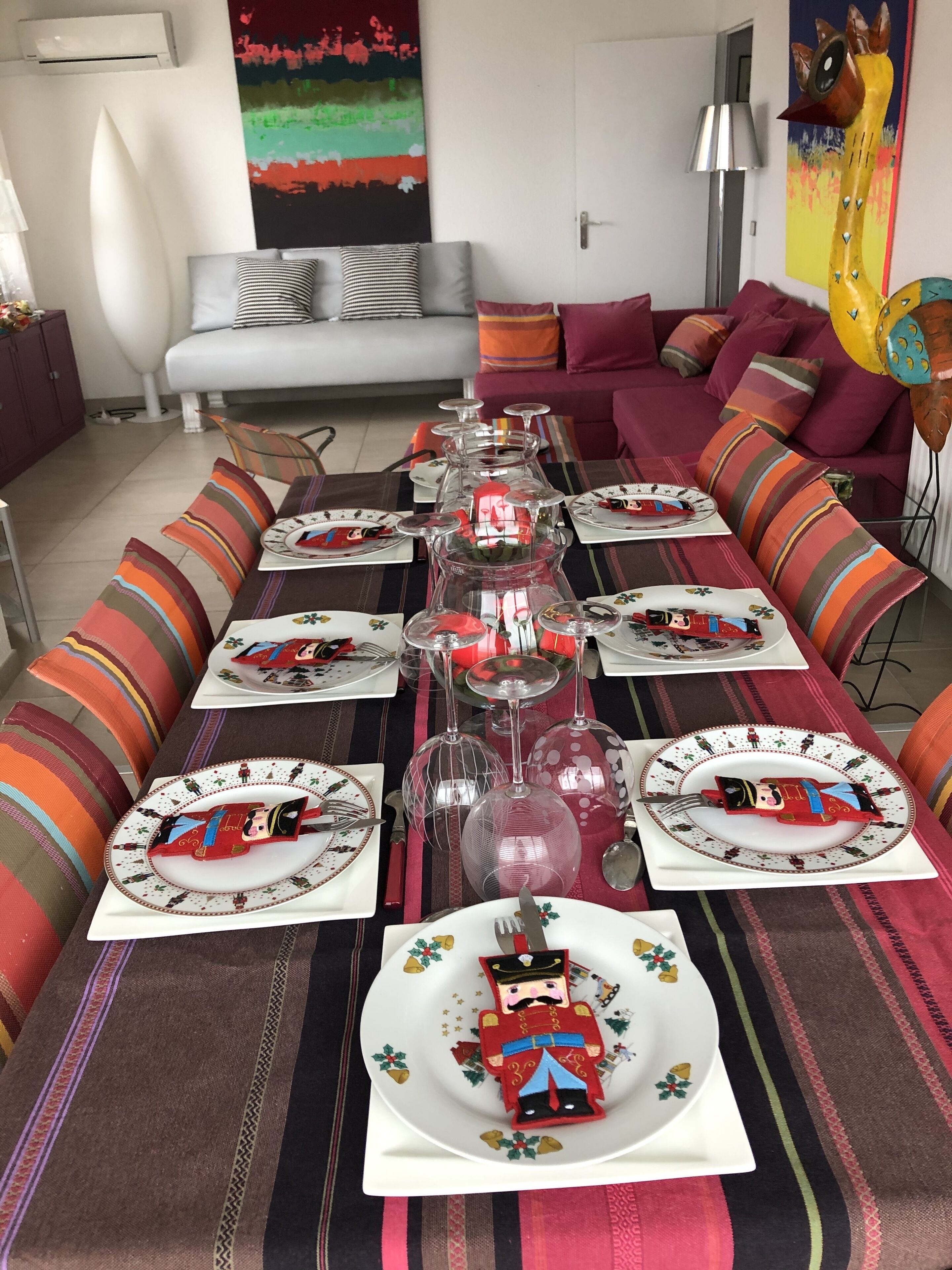 A dining table set with plates featuring nutcracker designs, surrounded by striped cushions and a colorful table runner.