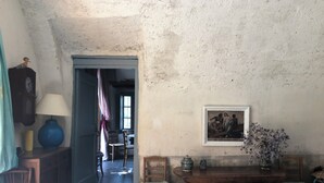 Une pièce rustique avec une table en bois, des chaises, une lampe bleue, une horloge et un tableau encadré accroché au mur.