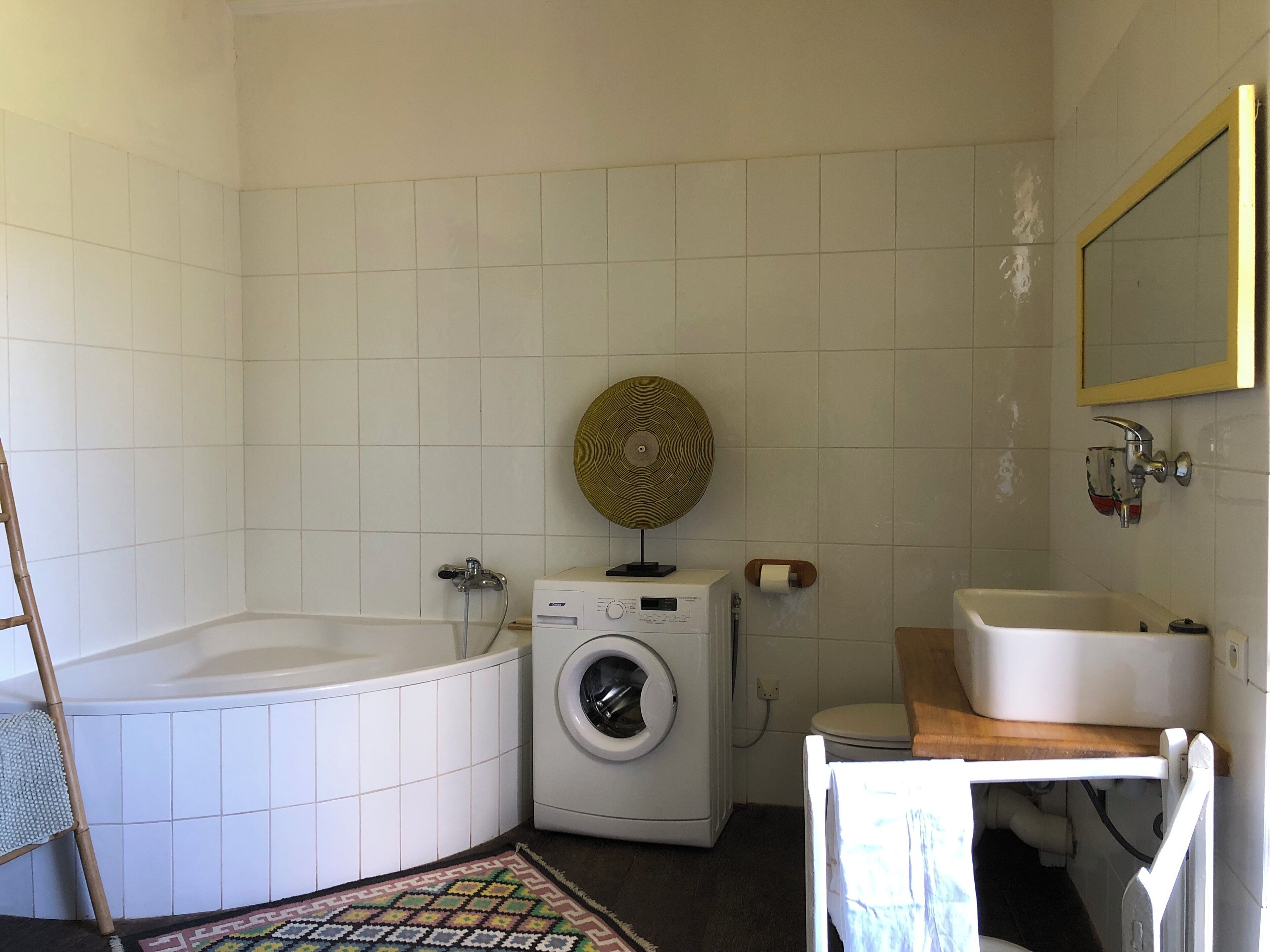 A small, clean bathroom with a bathtub, a washing machine, and a sink.