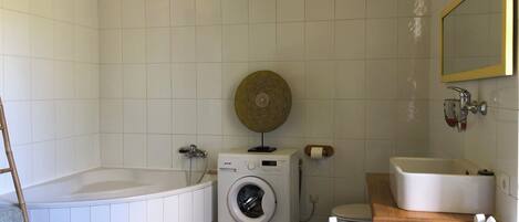 A small, clean bathroom with a bathtub, a washing machine, and a sink.