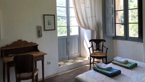 Une pièce avec un piano, une chaise, un lit avec des serviettes et une fenêtre avec des rideaux.