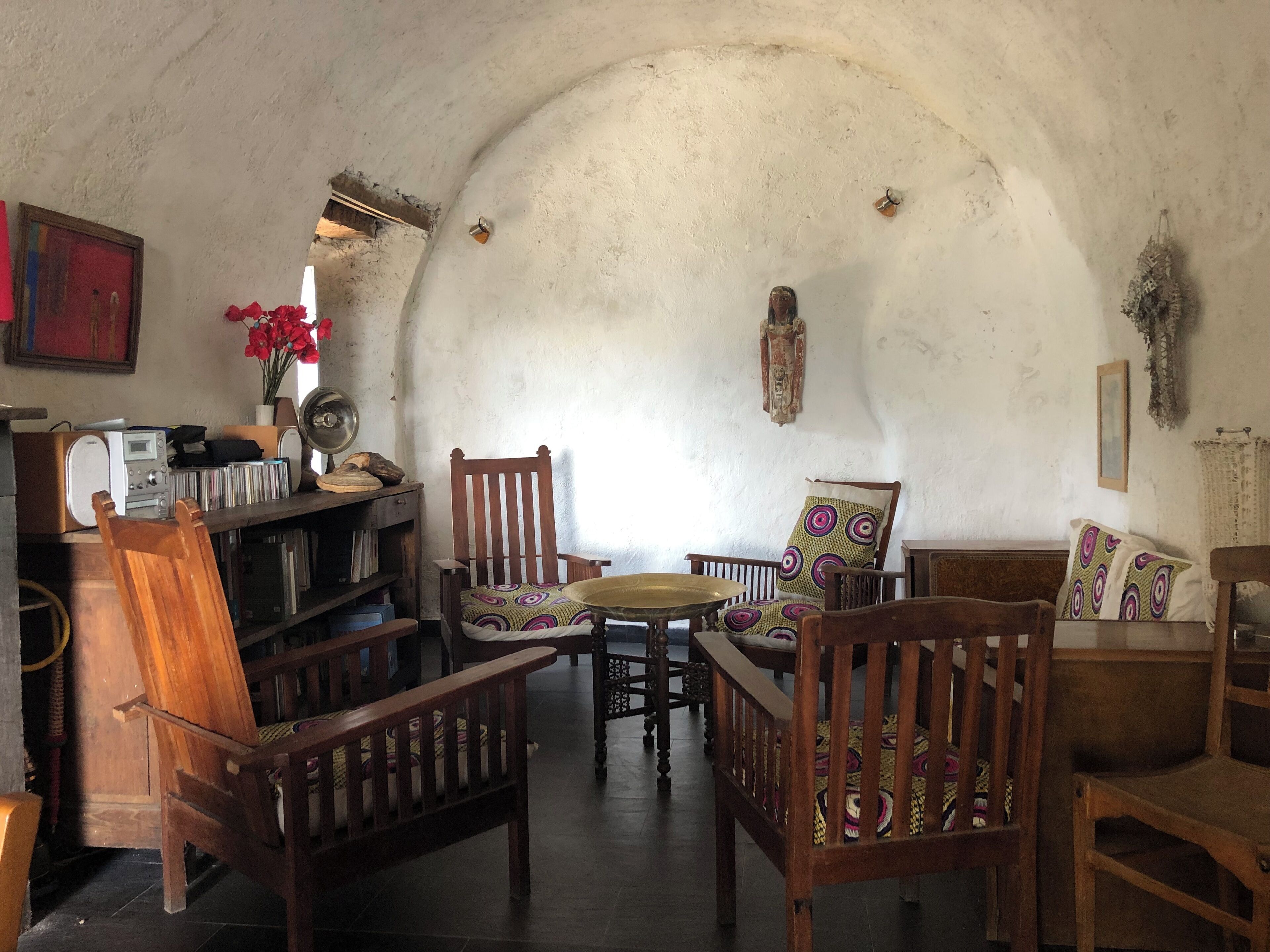 Ein rustikaler Innenraum mit Holzmöbeln, Fliesenboden und einer weißen, gewölbten Decke.