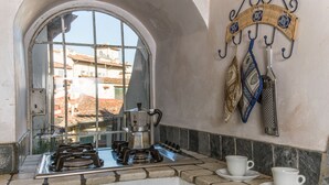 A kitchen with a gas stove, a coffee maker, and a hanging rack with utensils. - A Fantabulous Dreaming Terrace in FLORENCE Ponte Vecchio (Firenze)