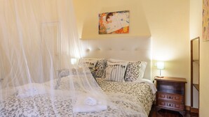 A bedroom with a bed covered in a canopy, a bedside table with a lamp, and a painting on the wall. - A Fantabulous Dreaming Terrace in FLORENCE Ponte Vecchio (Firenze)