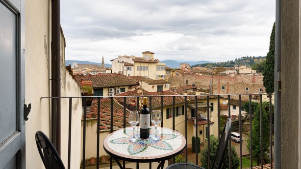 A balcony with a tiled table, a bottle of wine, and two glasses. - A Fantabulous Dreaming Terrace in FLORENCE Ponte Vecchio (Firenze)