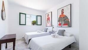 Une chambre d’hôtel moderne avec deux lits simples, une petite table et des œuvres d’art accrochées aux murs.