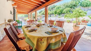A covered patio with a table set for dining, surrounded by chairs and potted plants. - Villa with exclusive swimming pool 5 minutes from the sea (Palermo)