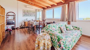 A cozy room with wooden beams, a bed with a cactus print, a dining area, and a bookshelf. - Villa with exclusive swimming pool 5 minutes from the sea (Palermo)