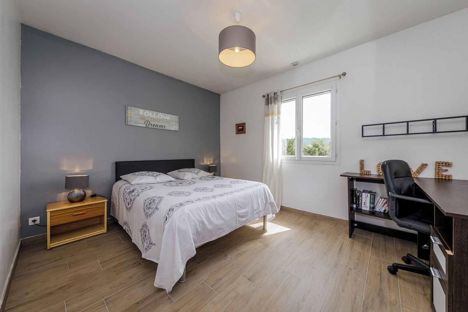 Une chambre à coucher comprenant un lit, une table de chevet, une lampe et un bureau avec une chaise.