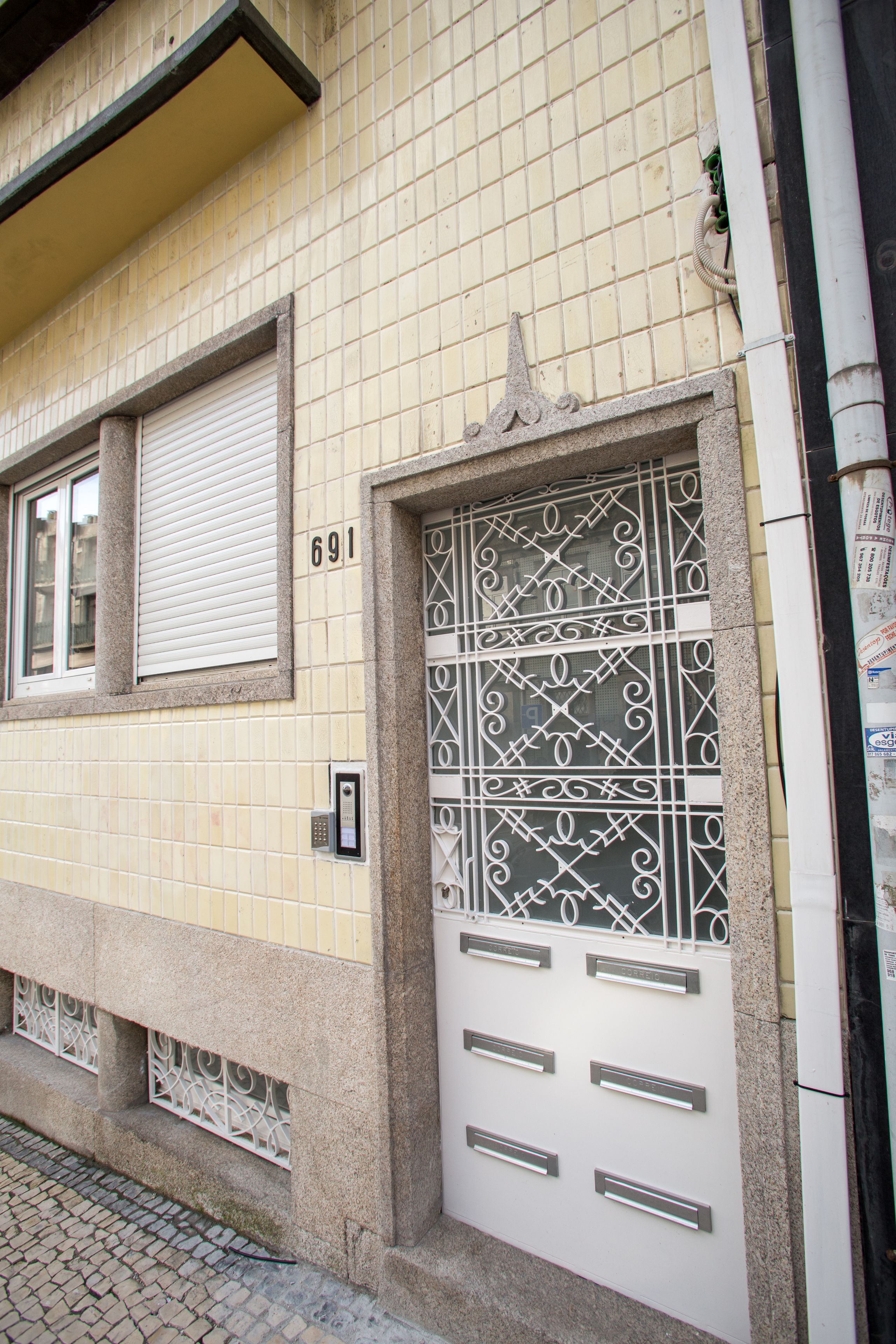 A building facade with a numbered door (691), decorative metalwork, and a window with a shutter.