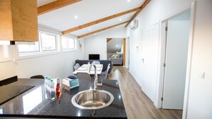 A kitchen with a stainless steel sink, wooden beams, and a dining area with a table and chairs.