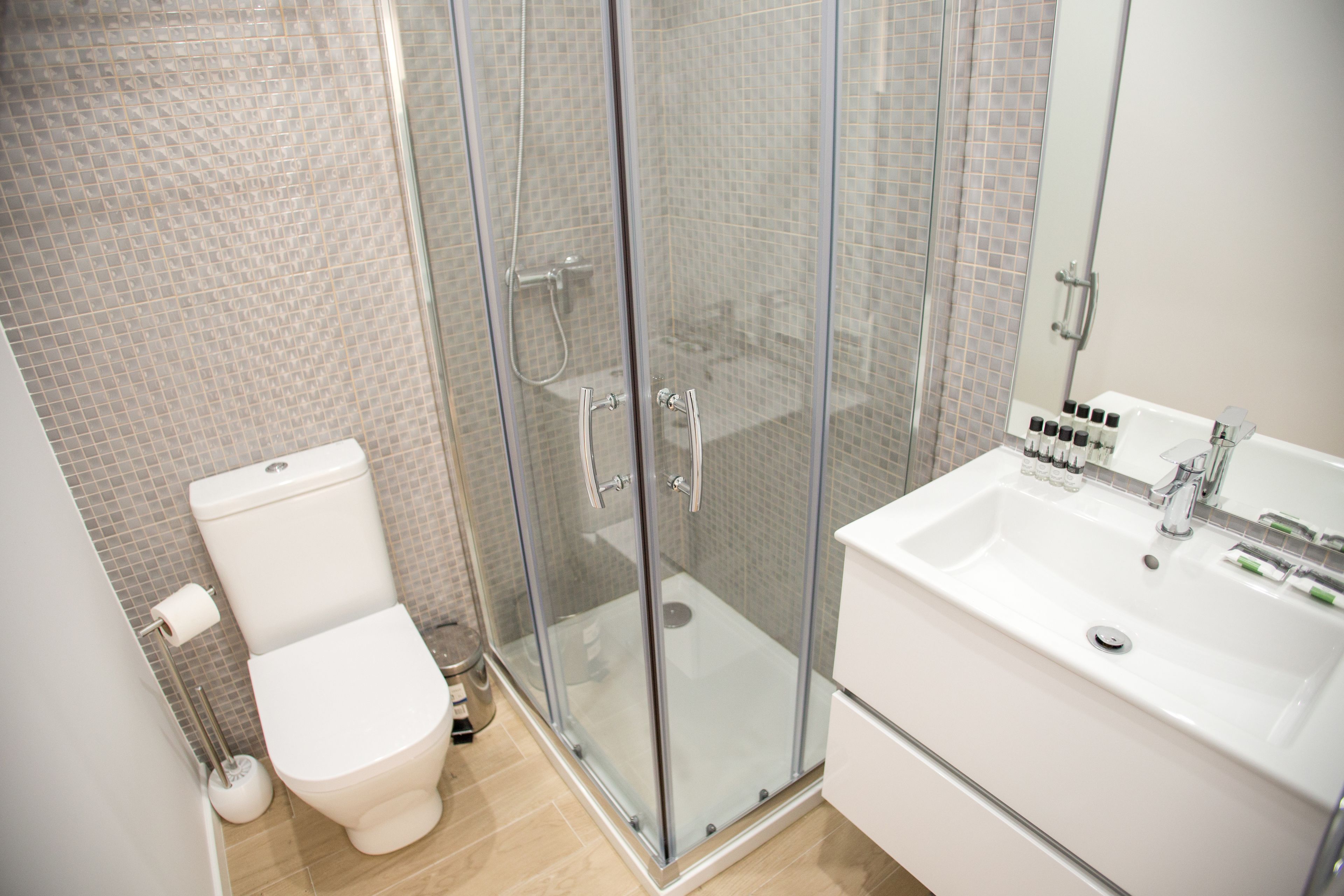 Ein modernes Badezimmer mit einer Duschkabine, einem weißen Waschbecken und einer Toilette.