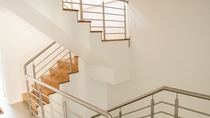 A modern interior with a staircase, metal railings, and a skylight.