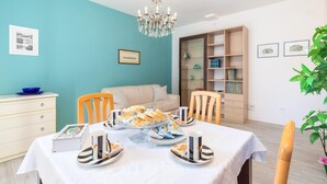 Un comedor con una mesa lista para comer, un sofá, una estantería y una araña.