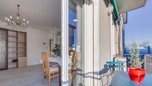 Un interior moderno con comedor, una araña y vistas al exterior.