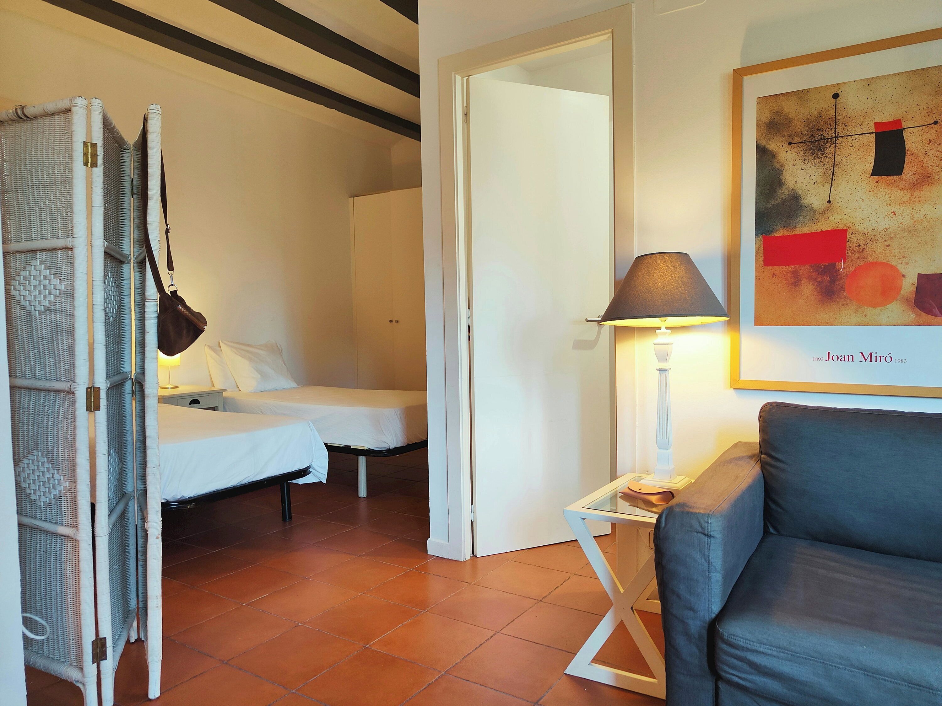 Ein Hotelzimmer mit zwei Betten, einer Sitzecke mit einem Sessel, einer Lampe und einem gerahmten abstrakten Gemälde.
