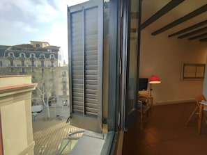 A balcony with a sliding door, a red floor lamp, and a view of buildings.