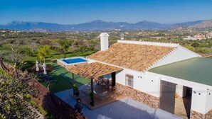 Una villa con piscina, un porche cubierto y vistas a las montañas.