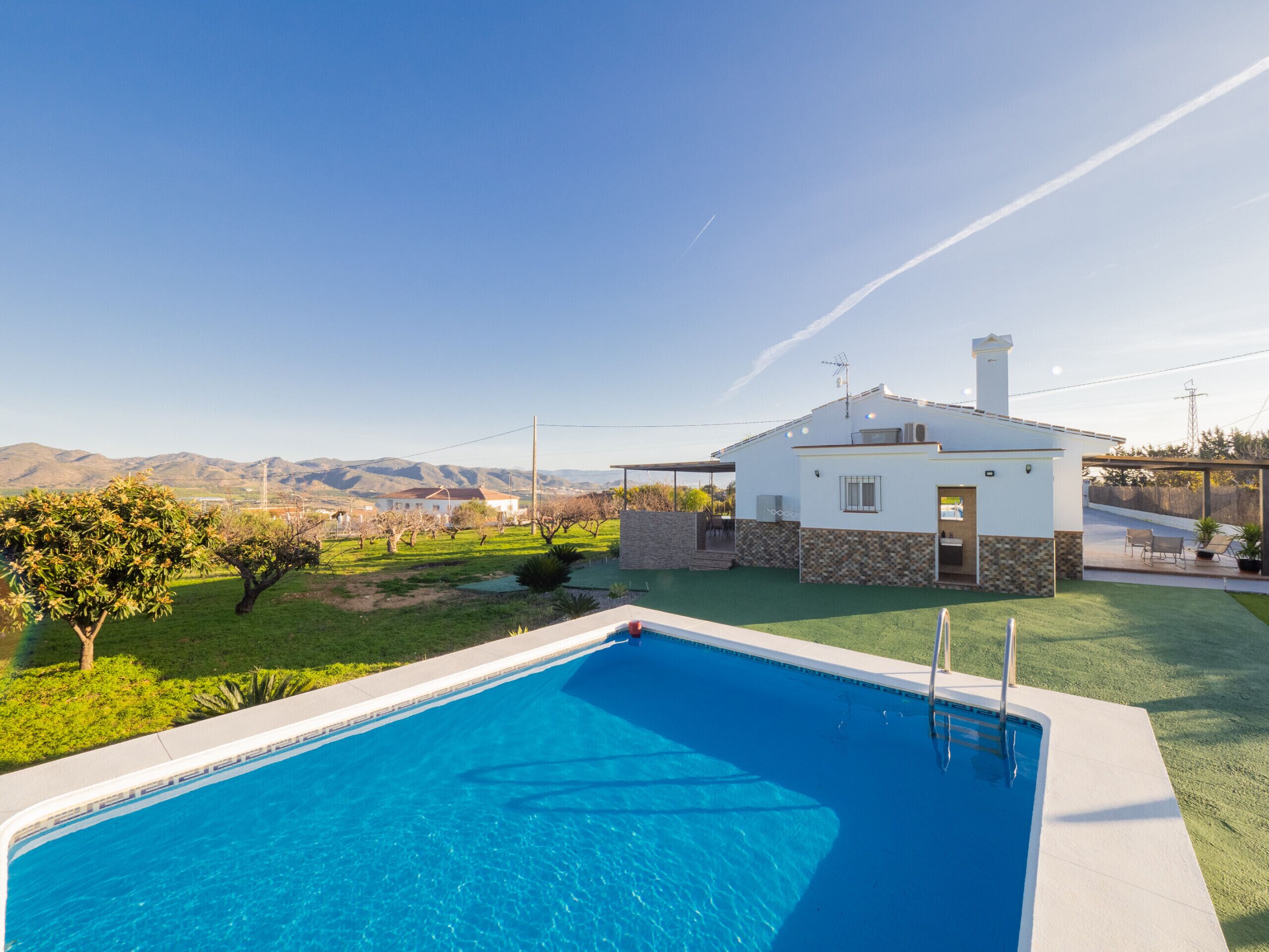 A swimming pool with a view of a white house and mountains in the background.