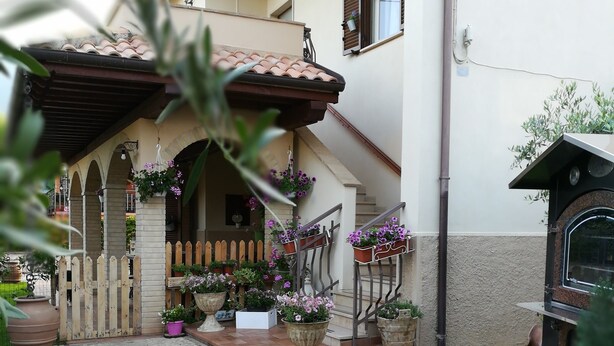 A courtyard with a stone pathway, a wooden fence, and potted plants. - SHABBY HOUSE GRANDMA PEPPA (Campello Sul Clitunno)