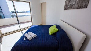 A bedroom with a large bed, a window, and a door. - Charming Huge PH with Private Rooftop and Jacuzzi (Playa Del Carmen)
