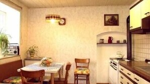 Una cocina compacta con armarios de madera, una mesa de comedor con sillas y un ventanal con plantas.