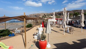 A beachside patio with outdoor seating, umbrellas, and a view of the sea.