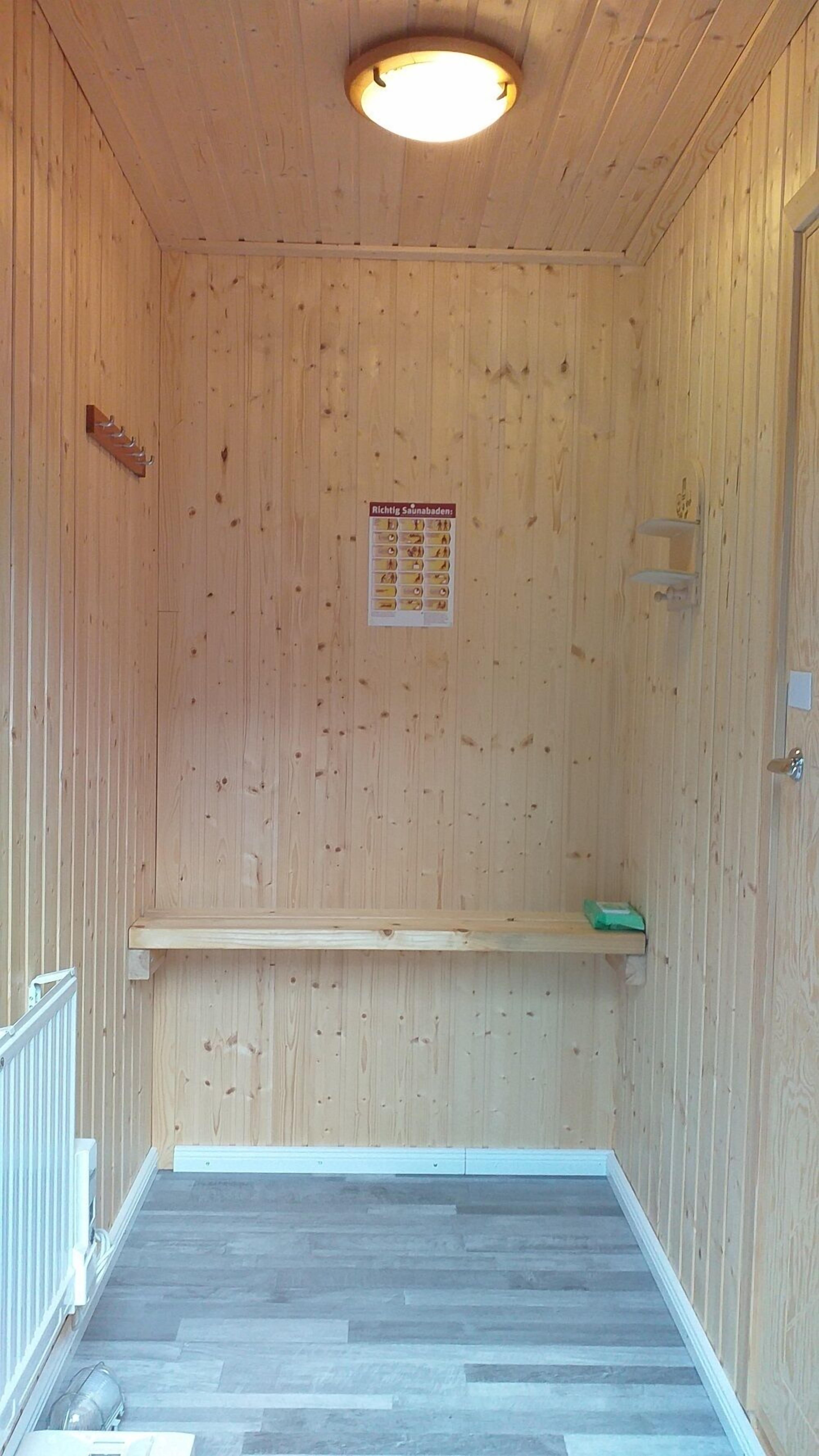 Un interior de madera con una lámpara en el techo, un banco de madera y un cartel en la pared.