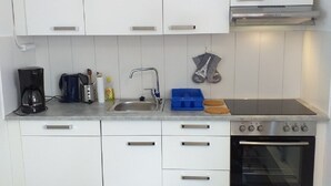 A compact kitchen with white cabinets, a sink, a stove, and a coffee maker. - Holiday home in the woods included Rowing boat - lake with jetty    (Vimmerby)