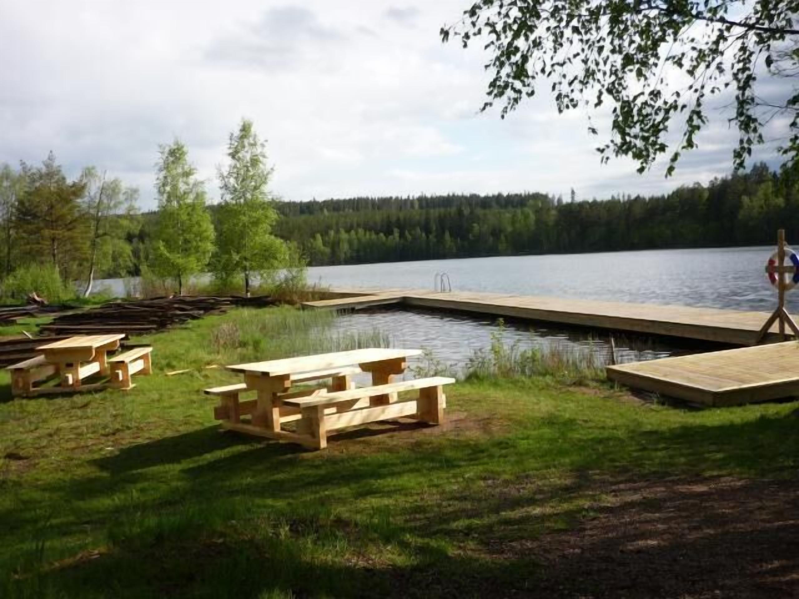 Un espace de pique-nique aménagé au bord du lac, avec des bancs en bois et une jetée qui s’avance dans l’eau.