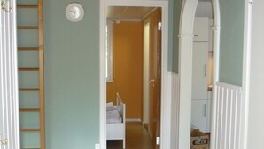 A hallway with a wooden ceiling, a bed in the adjacent room, and a ladder against the wall. - Holiday home in the woods included Rowing boat - lake with jetty    (Vimmerby)