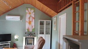 A living room with a television, a floral painting, a cabinet, and a wooden ceiling. - Holiday home in the woods included Rowing boat - lake with jetty    (Vimmerby)