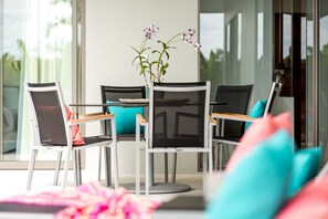 A modern dining area with a glass table, four chairs, and a vase of flowers. - 2 bed/2 bath Private Pool and Garden Villa - Stylish, Sophisticated and Fun! (Ko Samui)