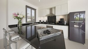 A modern kitchen with a central island, white cabinetry, and a stainless steel refrigerator.
