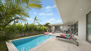 A modern outdoor pool area with a lounge chair and a flamingo float.