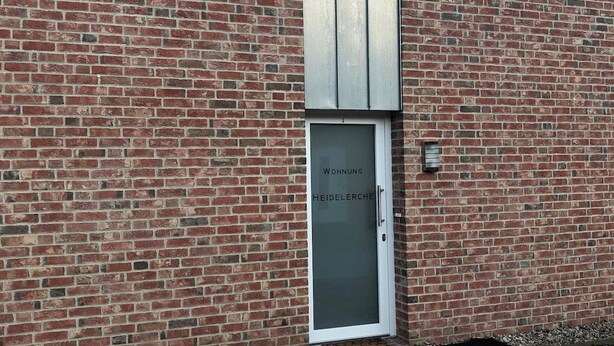 Un edificio in mattoni con una porta bianca con la scritta 'Wohnung Heidelederche'.