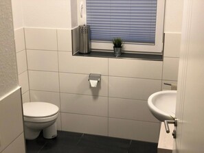 Un baño pequeño y limpio con inodoro, lavabo y ventana.