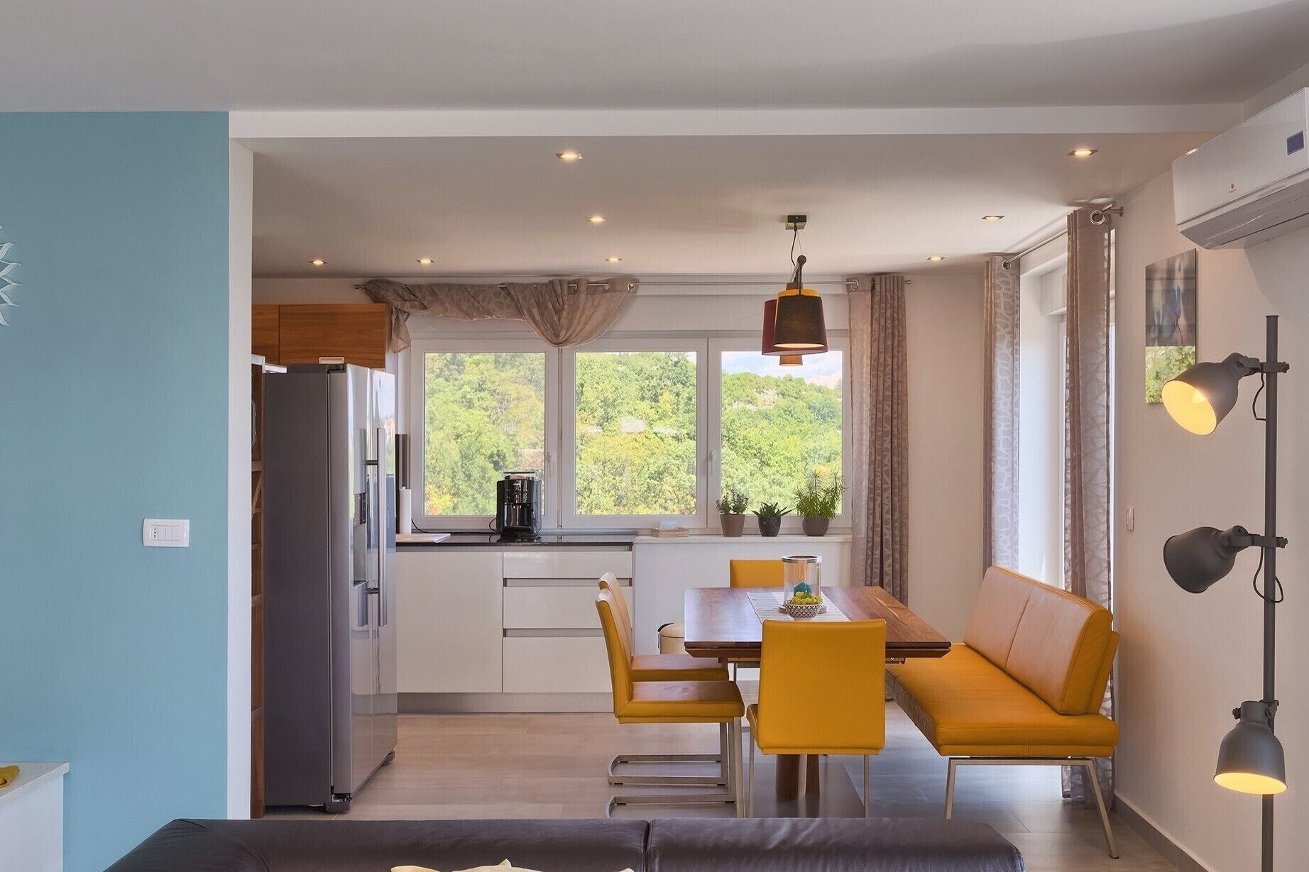 Une cuisine moderne avec un coin repas, comprenant un canapé et une table, et offrant une vue sur la verdure environnante.