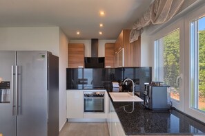 Enjoy cooking in this well-equipped kitchen with a stainless steel refrigerator, oven, and compact coffee machine.