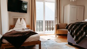A bedroom with a bed, a sofa, a television, and a view of the outdoors.