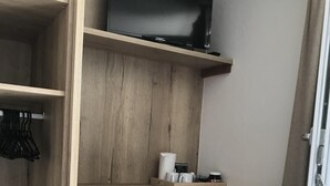 A compact room with a wooden desk, a chair, a television, and a radiator. - Wittner's B&B - small, fine and warm (Söll)