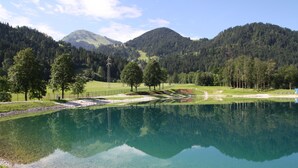 A clear lake reflecting trees and mountains, surrounded by grassy areas and a few buildings. - Wittner's B&B - small, fine and warm (Söll)